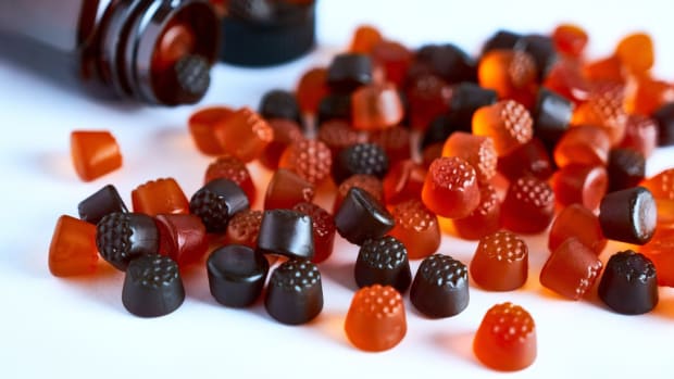 Berry-shaped gummy vitamins spilling out of a glass bottle